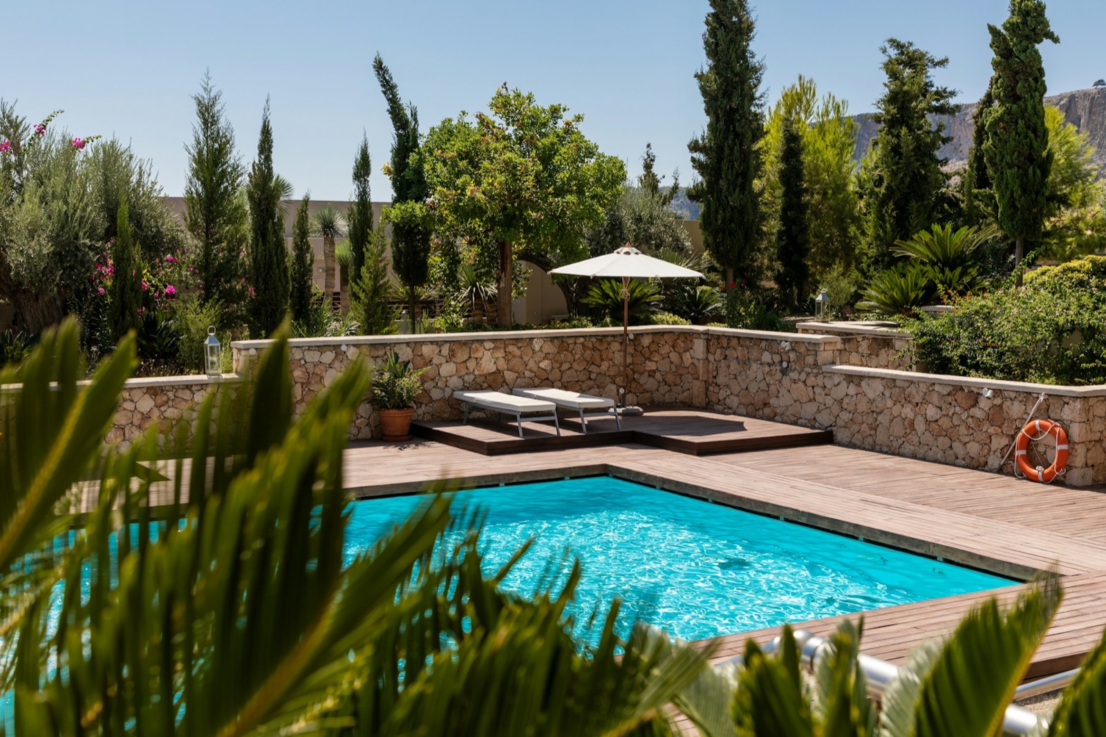 Sun-drenched poolside scene with white parasol and loungers